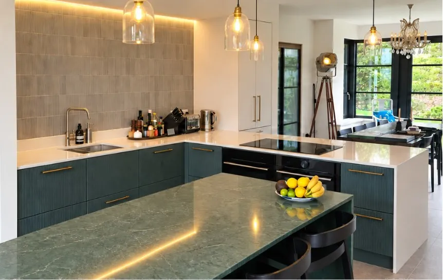 Finished Hove Park kitchen with textured Olivia dark green doors, brass handles, a Jardin Emerald quartz island and Desert Silver worktops