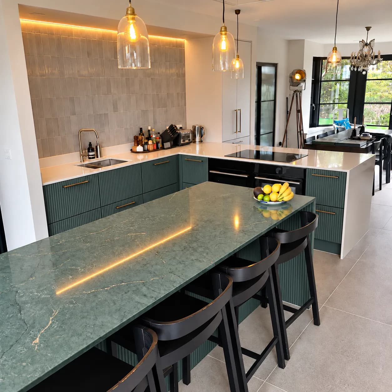 Finished Hove Park kitchen with textured Olivia dark green doors, brass handles, a Jardin Emerald quartz island and Desert Silver worktops