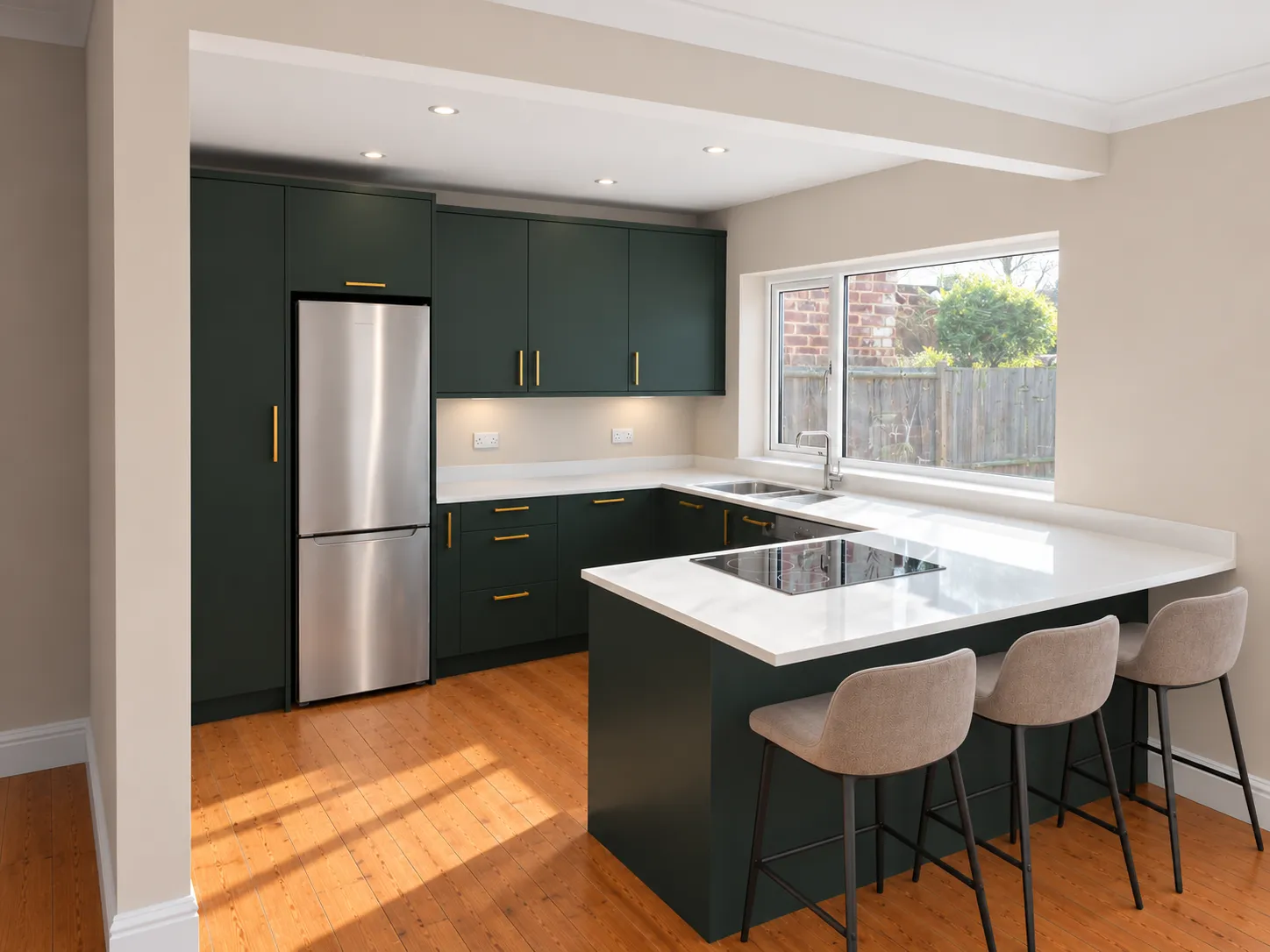 Finished kitchen with Fir Green slab doors, brass handles, Carrara White quartz worktops and a breakfast bar with stools